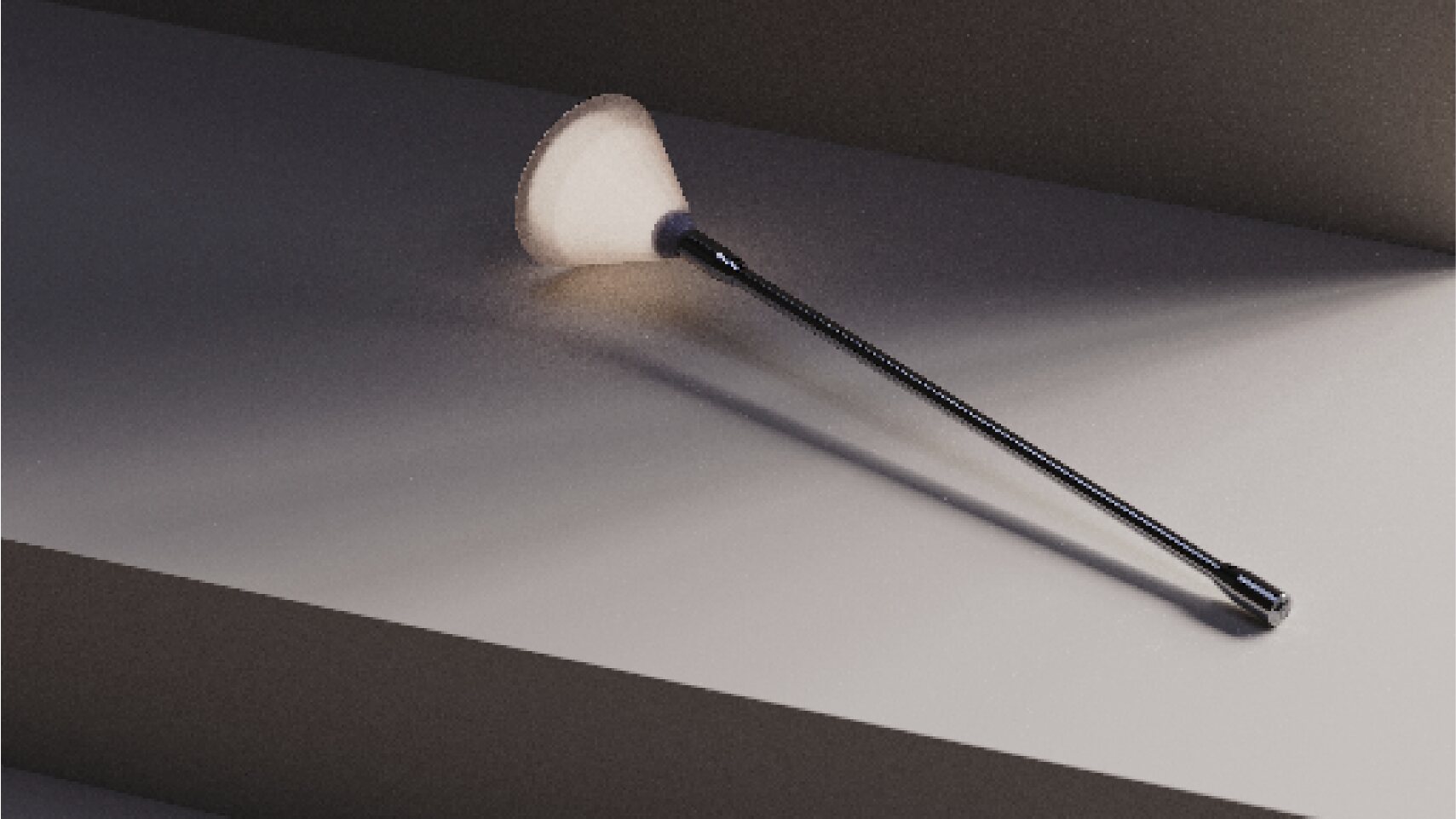Laleh portable light resting diagonally on a dark architectural surface